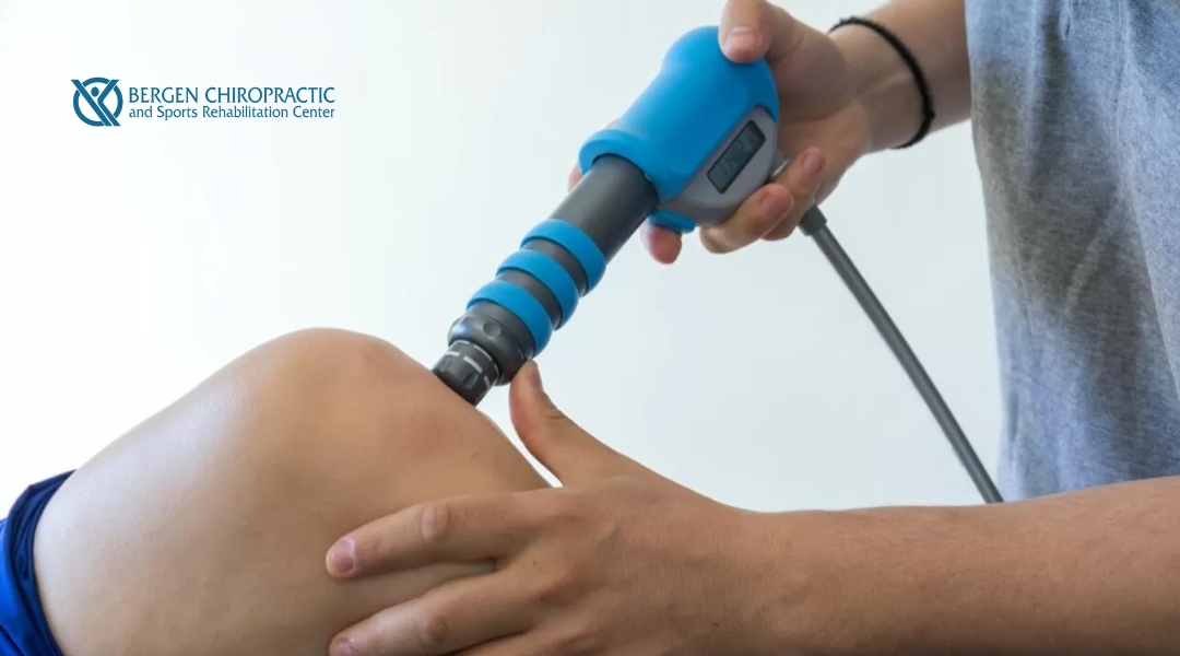 A practitioner is applying Extracorporeal Shockwave Therapy (ESWT) to a patient's knee using a handheld device with a digital display.