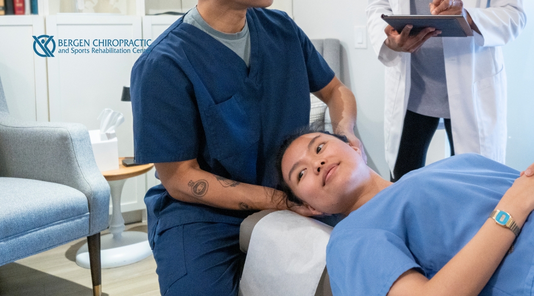 A student chiropractor practices a gentle cervical adjustment under supervision, while an instructor takes notes nearby at Bergen Chiropractic and Sports Rehabilitation Center.