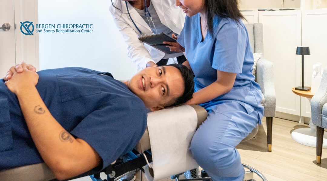 A chiropractic student in scrubs practices neck mobilization on a peer, with an instructor observing and providing guidance during a hands-on training session.