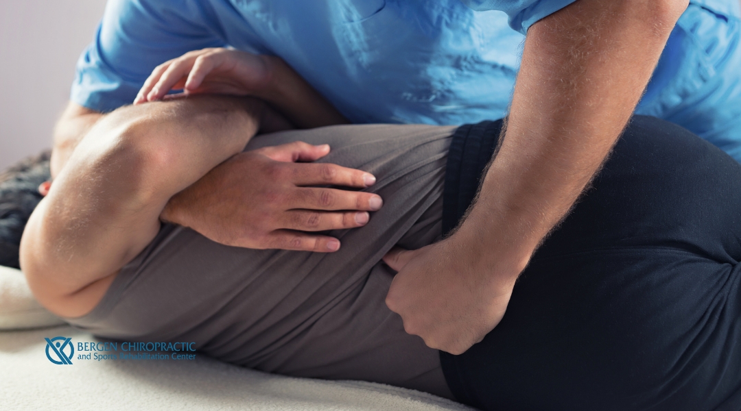 A chiropractor performing a spinal adjustment on a patient by applying pressure to the lower back in a clinical setting.