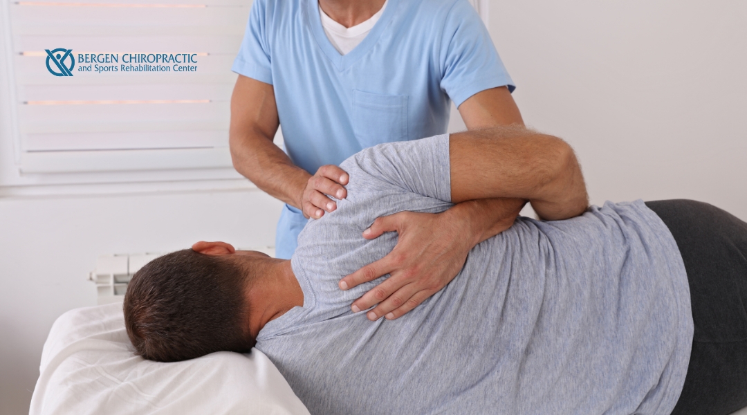 A chiropractor performing a thoracic spine adjustment on a patient lying on their side in a treatment session.