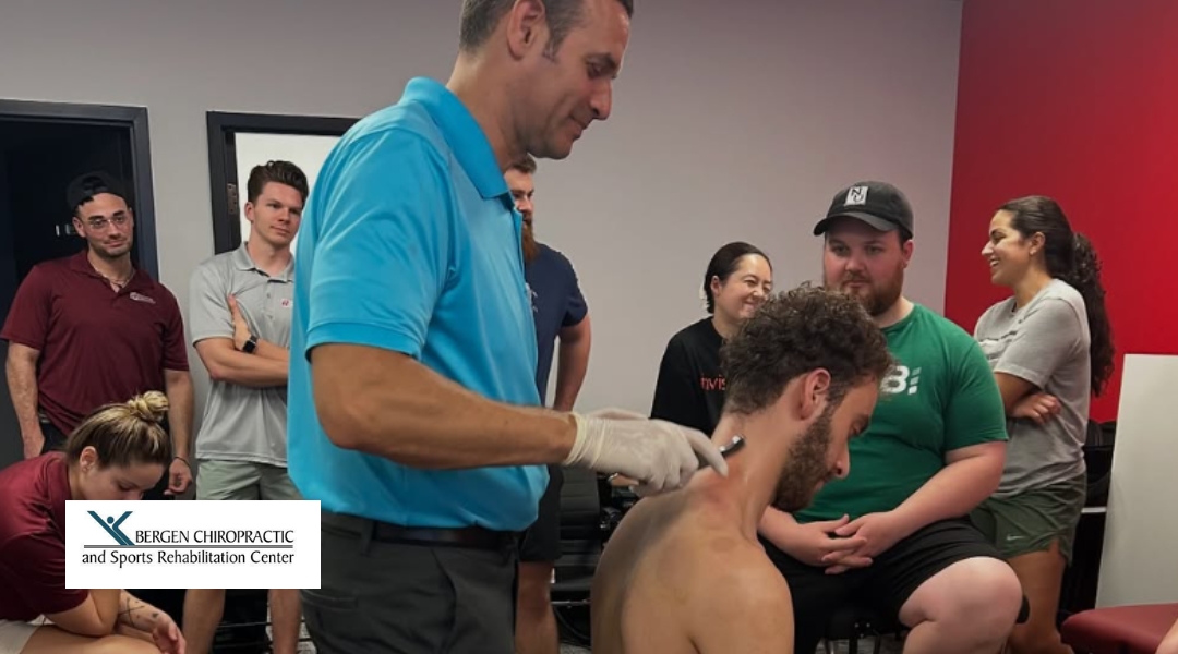 A chiropractor at Bergen Chiropractic performs a treatment on a patient’s back while several people watch in a learning environment.