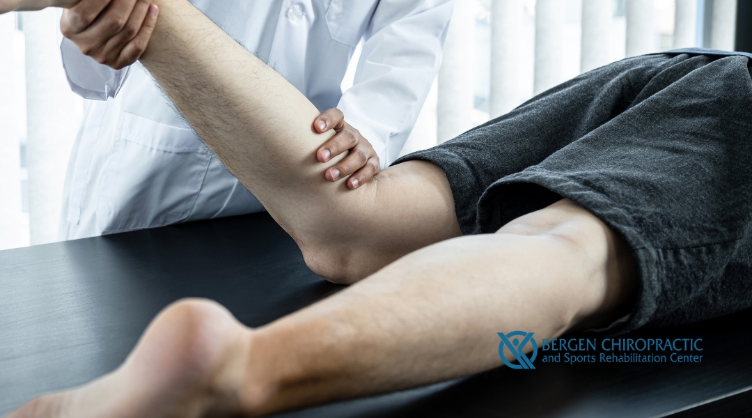 A chiropractor assisting a patient by stretching their leg during a therapy session, with the Bergen Chiropractic and Sports Rehabilitation Center logo in the corner.